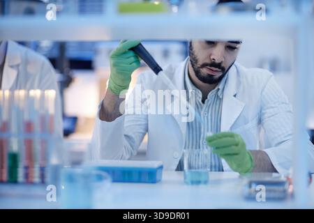 Young Adult Man Conducting Scientific Experiment in Laboratory Stock Photo