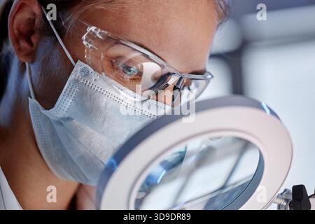 Caucasian Young Adult Woman Examining Sample through Magnifying Glass Stock Photo