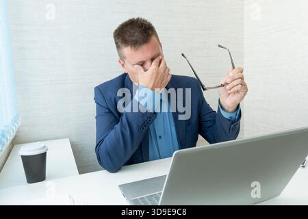 Thoughtful businessman looking at his laptop. a tired employee at work in front of a computer monitor. annoying work. A sad businessman. Stock Photo