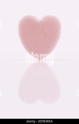 A single soft pink heart shaped makeup puff, suitable for applying powder, foundation, or removing makeup. The beauty product is isolated on a glossy Stock Photo