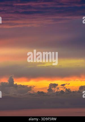 A soothing late-afternoon sky displays dramatic sunset colors, creating a magical fusion of glowing tones and softly lit clouds. Stock Photo