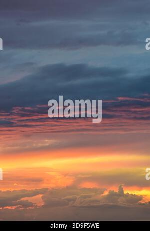 Radiant sunset tones gently illuminate the sky, revealing a blend of light, shadow, and soft cloud textures in quiet harmony. Stock Photo