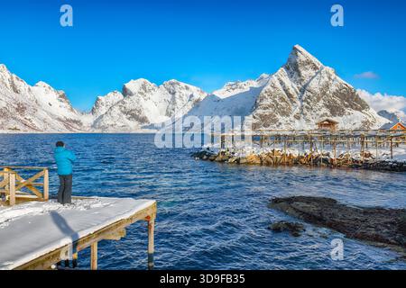 Photographer taking picture of Fantastic panorama of  Reinefjorden on Toppoya island with Olstinden peak. Location: Toppoya island, Lofoten; Norway, E Stock Photo