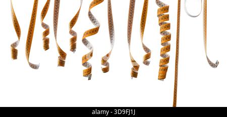 Collection of sewing measuring tapes hanging in various shapes in a row isolated on white background Stock Photo
