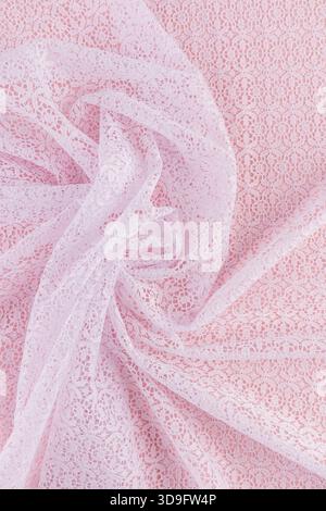 chic folds of white openwork fabric with floral ornaments on a pink background. The beauty and elegance of the delicate waves of textiles. vertical Stock Photo