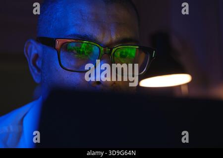 Man wearing glasses with cryptocurrency market data reflecting in lenses at night Stock Photo