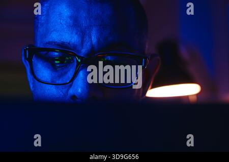 Person wearing glasses with market data reflection, actively engaging in online finance Stock Photo