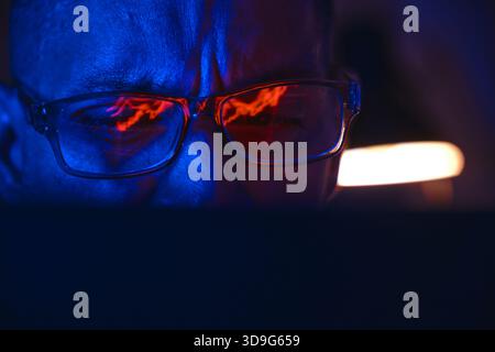 Close-up of a person analyzing stock charts and cryptocurrency data on a screen in glasses Stock Photo