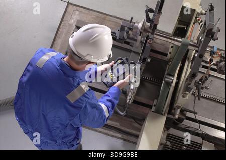 Technician using testing device to monitor vibration in manufacturing equipment, New York, USA Stock Photo