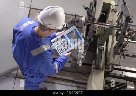 Technician using testing device to monitor vibration in manufacturing equipment, New York, USA Stock Photo