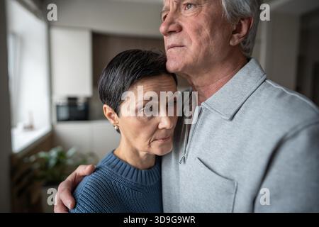 Senior woman in husband embrace comforting thoughtful sad mood. Marital support in hardships, empathy of senior family, love elderly care, health issues, soothing consoling partner, aging bonding || Model released Stock Photo