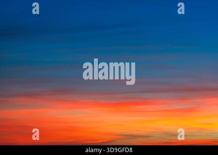 Vibrant background texture of an autumn sunset sky, captured from Tuscany in November 2025. The colors transition from blue at the top to fiery red, o Stock Photo