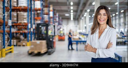 Warehouse manager standing near cardboard boxes background. Stock Photo