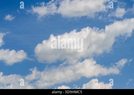 Capture of fluffy white clouds drifting peacefully in a bright and vibrant blue sky, showcasing their beauty Stock Photo