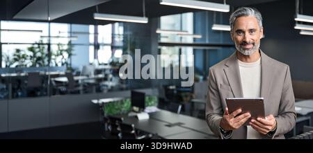 Happy mature business man ceo executive standing in office with tablet. Stock Photo