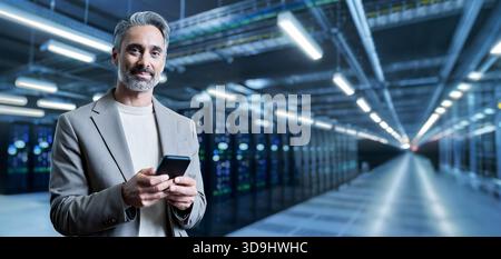 Happy mature business man using smartphone in server room. Portrait. Stock Photo