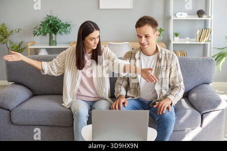 Couple sitting on sofa in living room at home using laptop together discussing repair projects Stock Photo