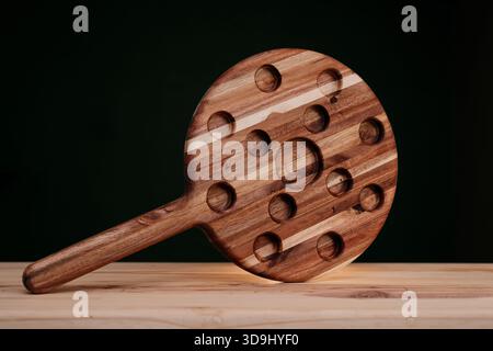 Hardwood shooter board on a light wood surface with a dark green background Stock Photo