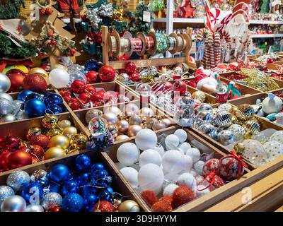Multiple colorful christmas ornaments and festive decorations filling wooden boxes and shelves at a holiday market Stock Photo