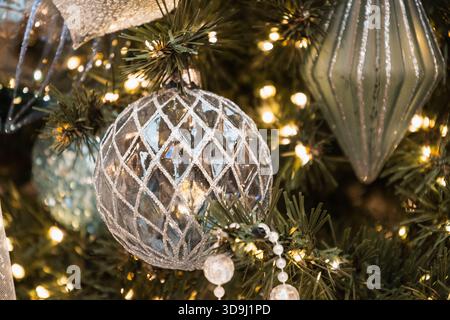 Blue lattice ornament on Christmas tree with warm festive lights and shimmering winter decor. Stock Photo