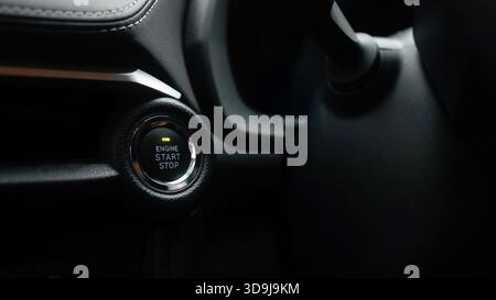 Detailed close-up of ignition button in vehicle, highlighting engine start stop function, surrounded by stylish dashboard materials and modern design Stock Photo