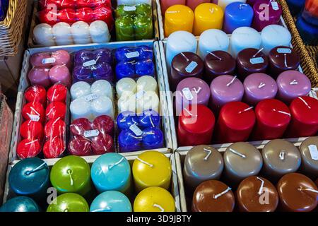 A display of assorted colorful wax candles arranged in rows at a festive market stall. Colorful candles with price stickers at a fair stand Stock Photo