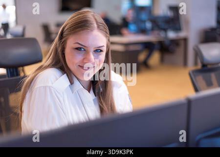 Professional female security officer working in a modern surveillance control room. Stock Photo
