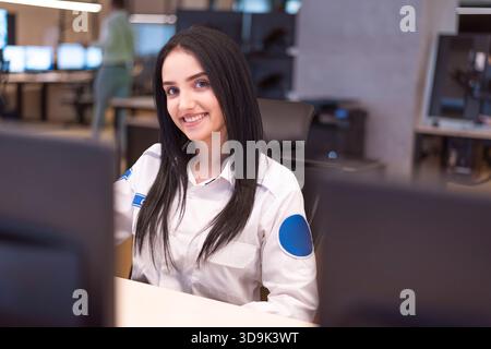 Professional female security officer working in a modern surveillance control room. Stock Photo