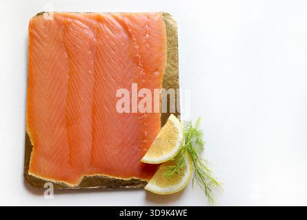 Thinly sliced ​​smoked salmon, garnished with lemon wedges and fresh dill isolated on a white background. Seafood. Overhead view. Stock Photo