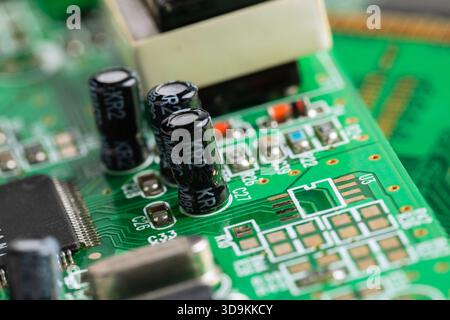 Green PCB detailed with capacitors, resistors, and a microchip. Intricate connections power modern electronics. Stock Photo