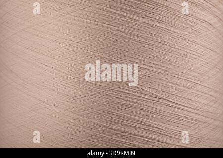 A close-up view of a light pink thread spool. Macro shot of a pink polyester string. Stock Photo