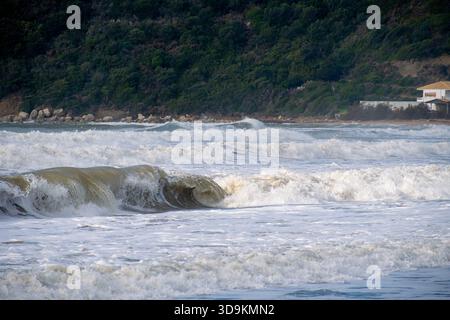 Telephoto shot of large muddy waves crashing with force on the shore during a winter storm in Corfu Greece highlighting the raw power of nature and da Stock Photo