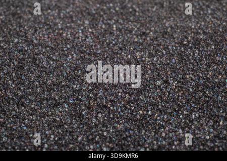 An extreme close-up of a, rough surface reveals a dense, sparkling texture composed of tiny, multicolored, granular particles Stock Photo