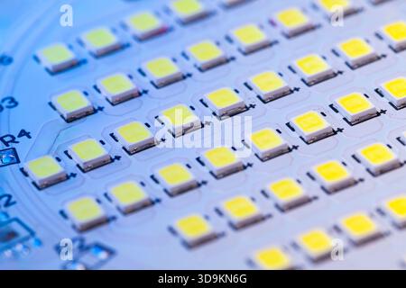 Blue light illuminates an electronic board covered in LED modules, showcasing a close-up assembly of Light Emitting Diodes. Stock Photo