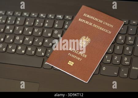 Austria passport lies on black laptop keyboard buttons background close up. Technologies and control in Europe concept Stock Photo