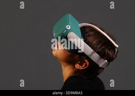 Side view of boy using VR headset and handheld controller, fully engaged in immersive digital gameplay. Stock Photo