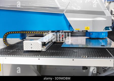CNC punching machine processing a metal sheet in an automated industrial facility, used for precision sheet metal fabrication and high-efficiency manu Stock Photo