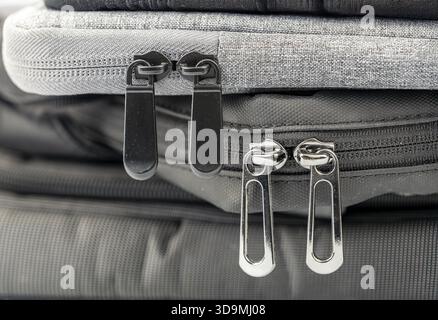 This close-up image showcases the intricate details of zippers and fabric on stacked bags. Different textures feature prominently, highlighting the co Stock Photo