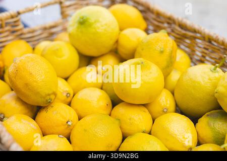 Lemons resting in woven wicker basket sitting on wooden countertop under soft natural lighting Stock Photo