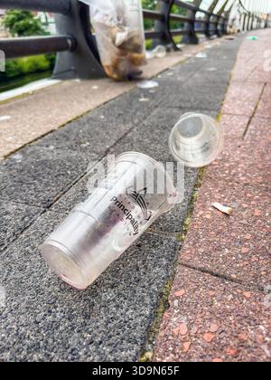 Cardiff, Wales, UK - 20 June 2025: Empty plastic beer cup on the floor with other rubbish after a rock concert at the city's Principality Stadium. Stock Photo