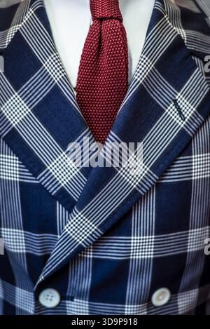 Detail of a double-breasted tailored suit jacket (in a blue broad check or plaid pattern), red neck tie and white dress shirt Stock Photo