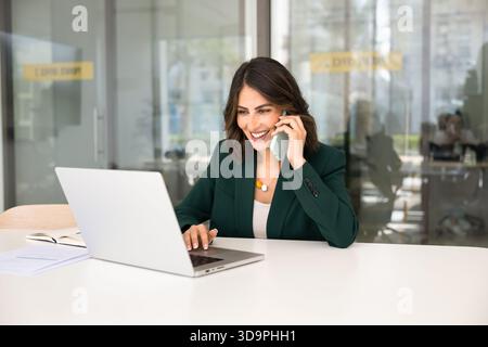 Positive young manager woman talking to client on mobile phone Stock Photo