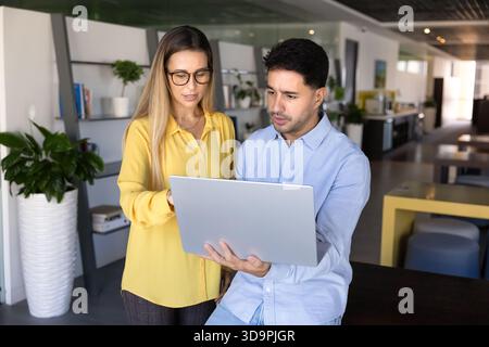 Two focused busy young professionals working on online task together Stock Photo