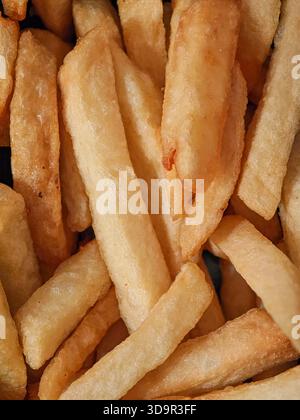 Crispy, golden French fries are stacked in a bowl, showcasing various shapes and sizes. Perfect for sharing or as a tasty side, these fries invite app Stock Photo