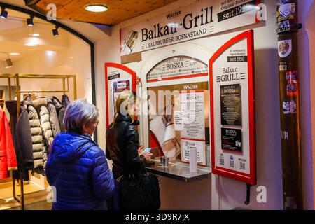 Customers ordering at the Balkan Grill food stand in Salzburg, Austria, known for its traditional Bosna sausage. Stock Photo