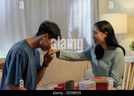 Happy young couple shows romantic love at home man kisses woman hand on valentine day expressing Stock Photo