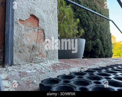The outer layer of insulation of a house thermal insulation composite system is damaged and the components are crumbled on the floor, in the backgroun Stock Photo