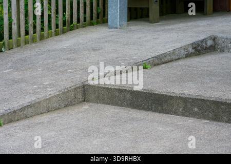 he photo shows sturdy concrete steps alongside a smooth ramp designed for bicycles or wheelchair access. A wooden fence blends into the background, ad Stock Photo