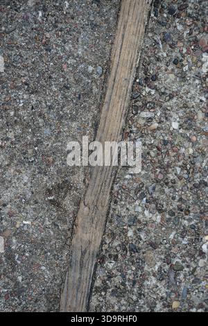 A textured pathway made of small stones mixed with concrete features a striking wooden inlay down . The combination creates an interesting contrast be Stock Photo