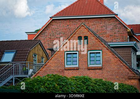 A row of charming red brick houses with tiled roofs shows one two floors home featuring green and white windows and an outdoor metal staircase surroun Stock Photo